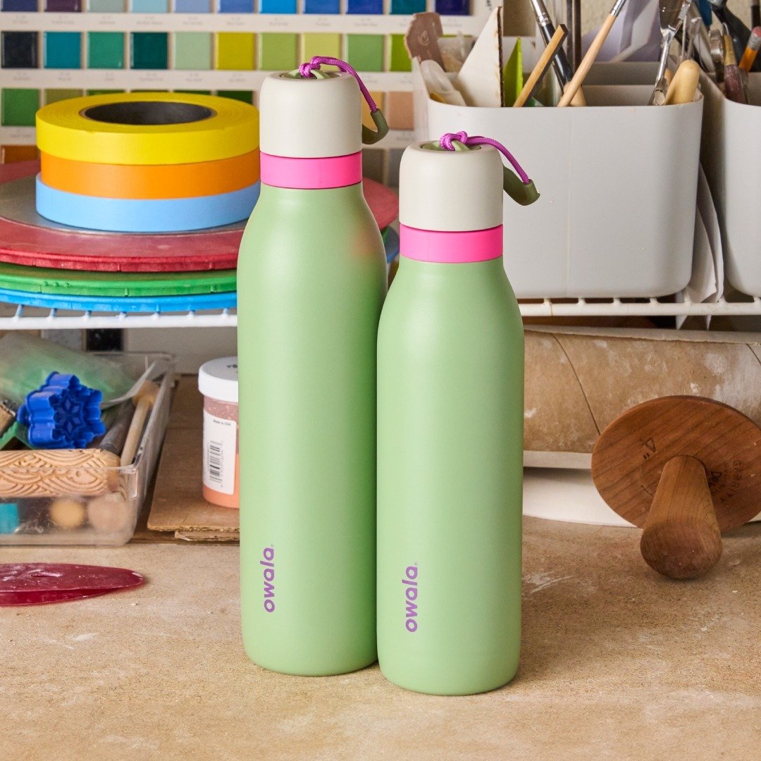 Duas Garrafas Térmicas Owala Twist - 532ml | 18oz verdes em um estúdio de arte colorido, destacando praticidade e desempenho térmico.