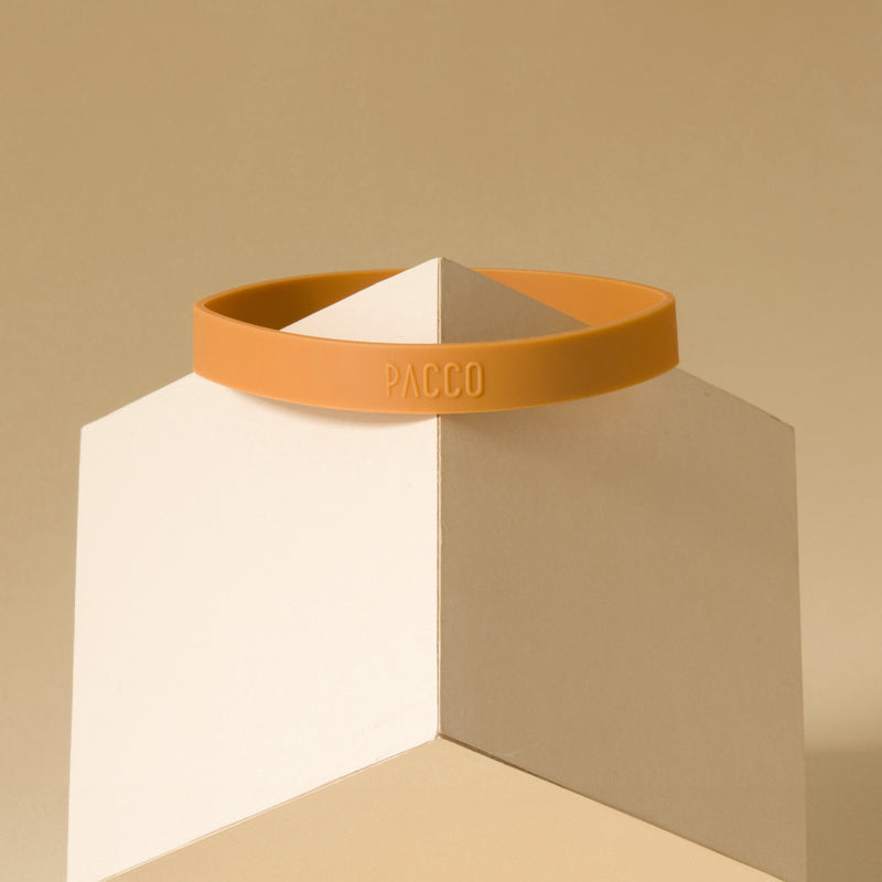 Anel de Silicone PACCO em amarelo sobre bloco, design ergonômico e aderente, toque de estilo e conforto para garrafas.