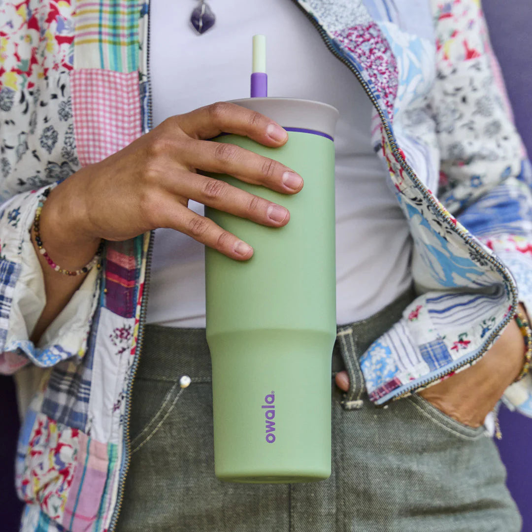 Pessoa segurando Copo Tumbler Térmico Owala - 710ml | 24oz verde, com design moderno e capacidade de manter a temperatura da bebida.