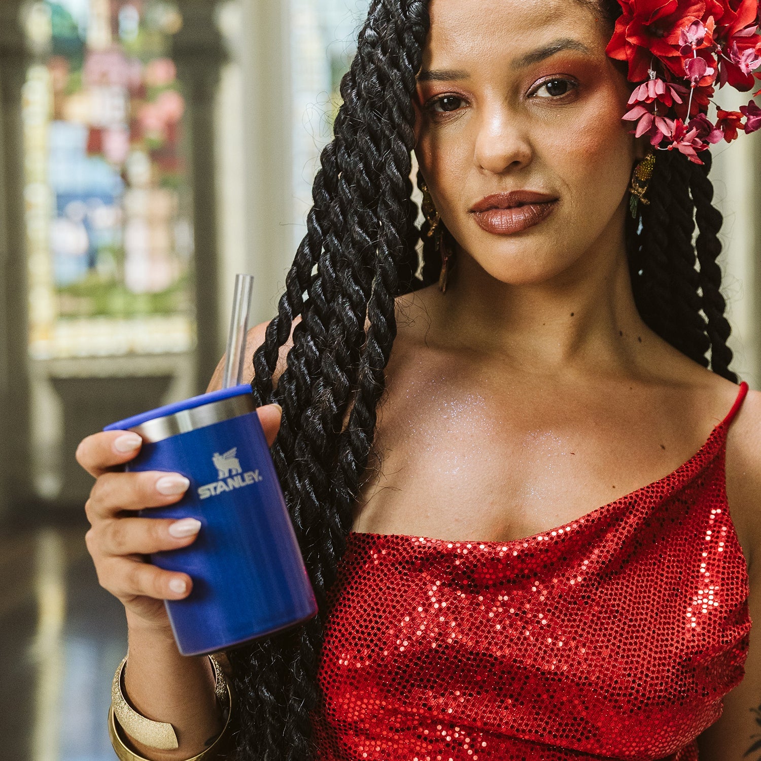 Can Cooler com canudo Stanley | 296ML em mãos de mulher com cabelo trançado e vestido vermelho brilhante.