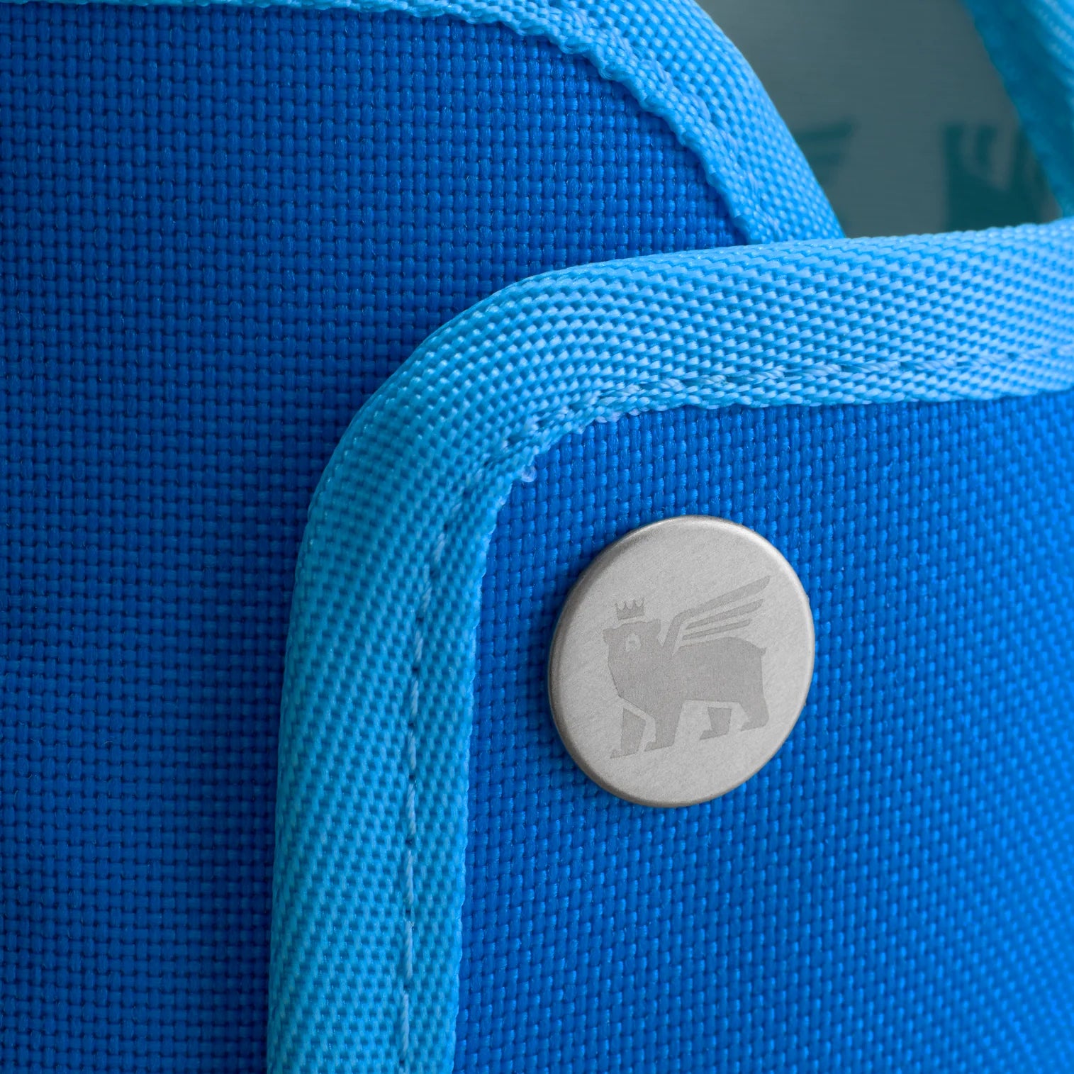 Detalhe do botão e tecido azul da Bolsa para Copo Quencher Stanley - Carry All 1,18L, com padrão de urso alado.
