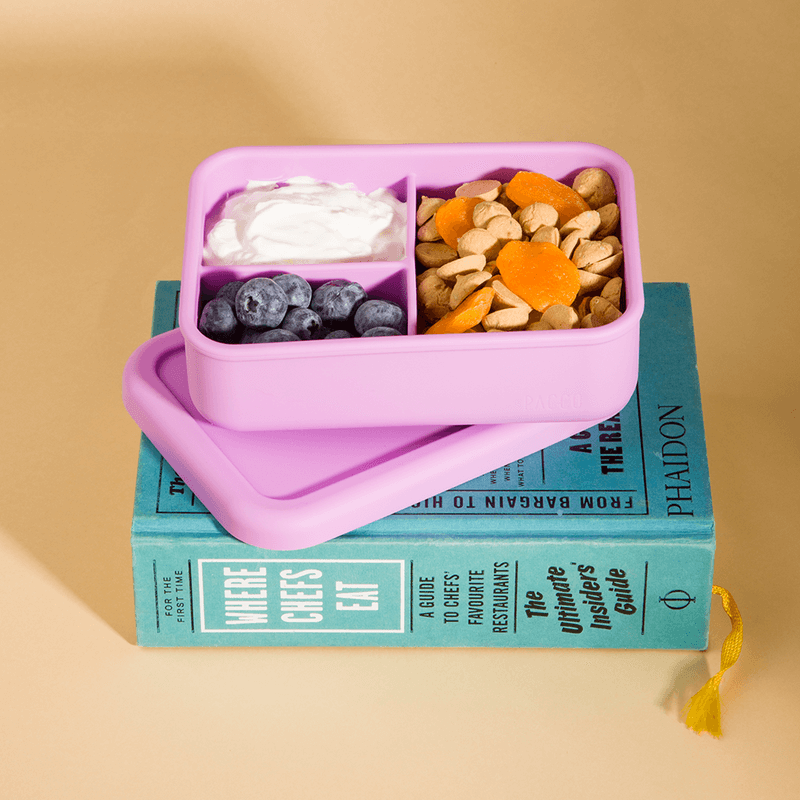Lunch Box em Silicone - PACCO com divisórias inteligentes para alimentos saudáveis, sobre livros. Compacta e ecológica.