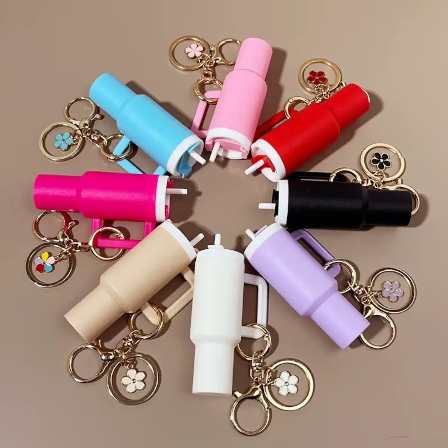 Chaveiro Copo Stanley Quencher em várias cores dispostas em círculo com detalhes de chaveiros decorativos.