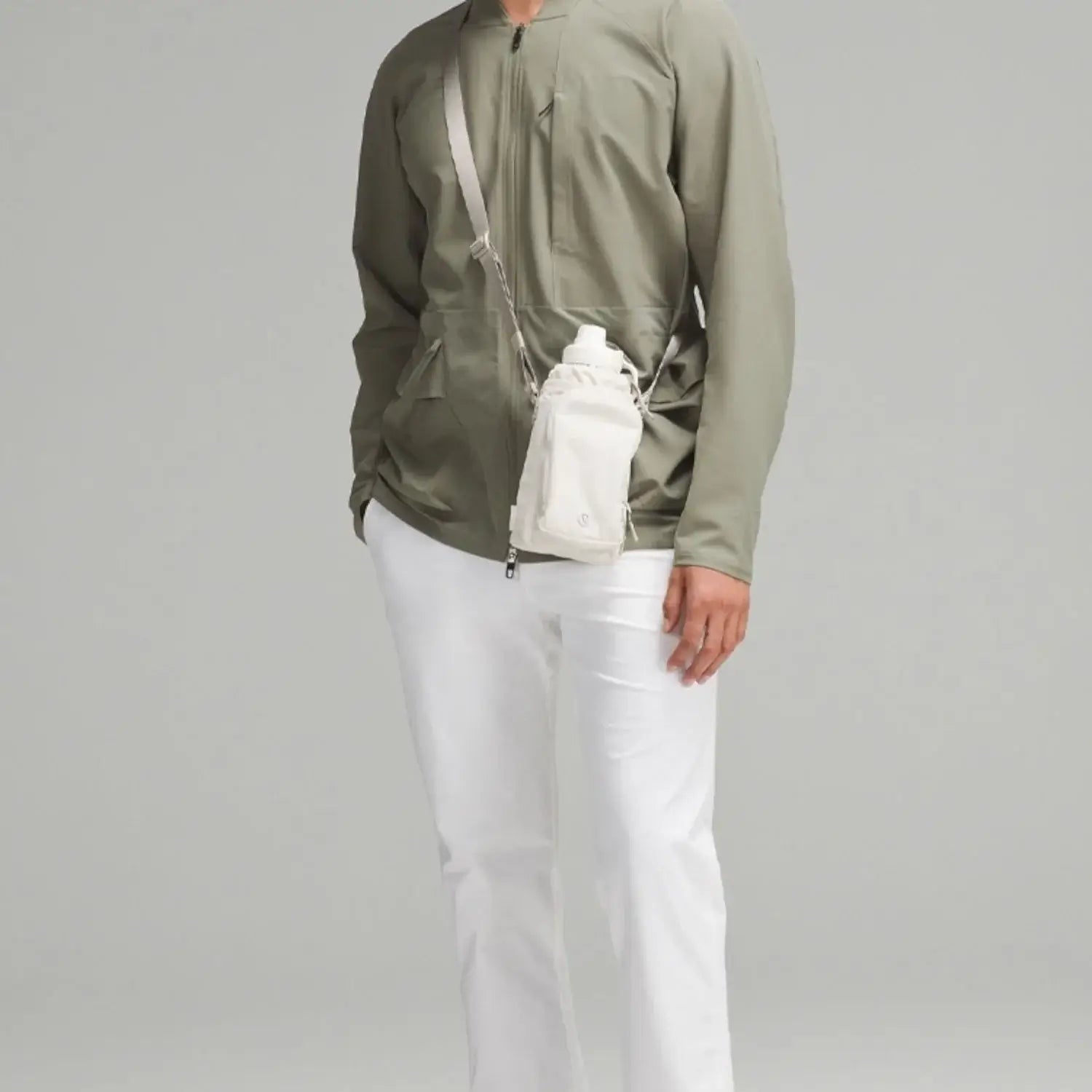 Bolsa para Garrafa Térmica - Cross Bottle Lululemon, estilo crossbody, usada por pessoa com roupa casual verde e branca.