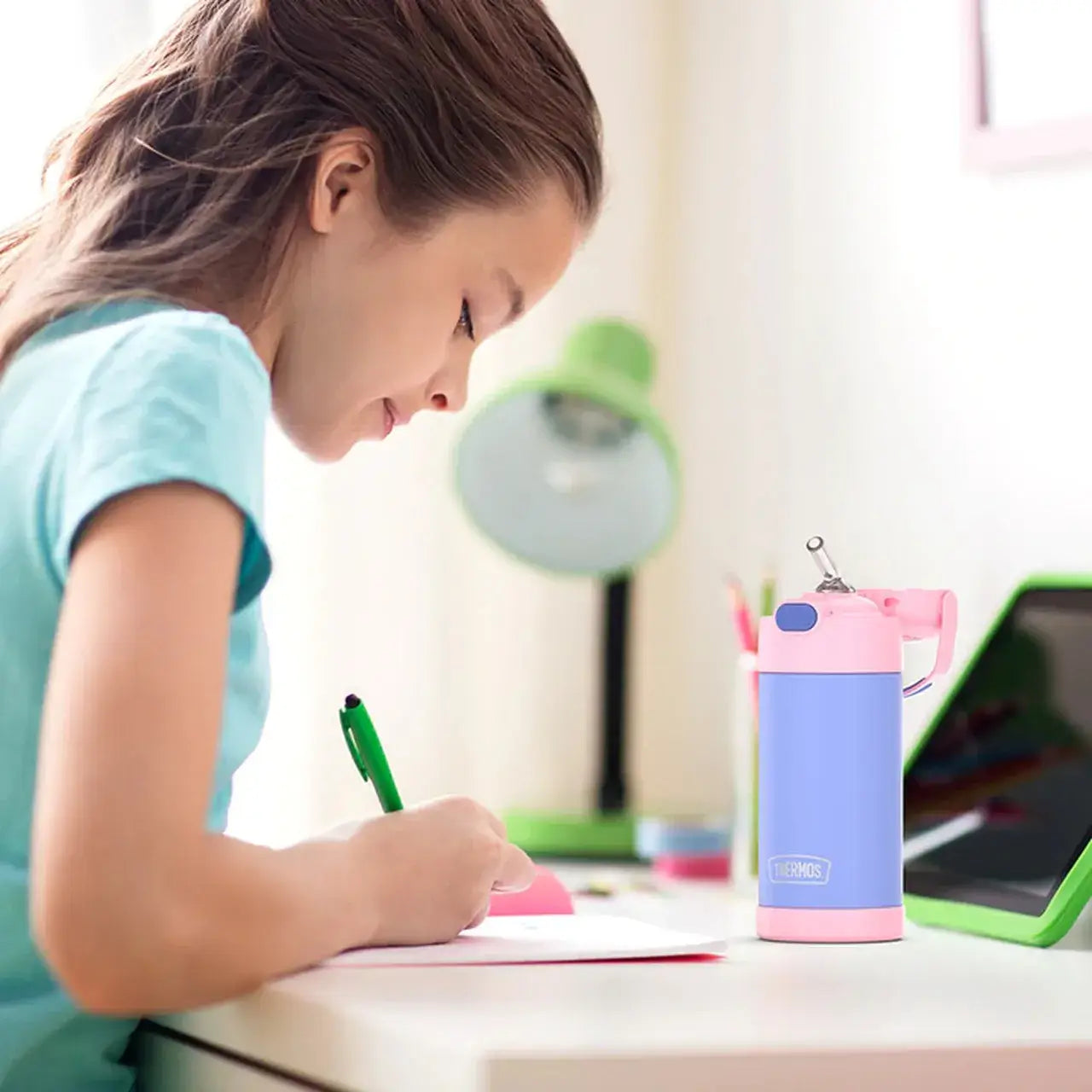 Criança estudando com Garrafa Térmica Funtainer Thermos - 355ml ao lado, garrafa azul e rosa, promovendo hidratação segura e divertida.