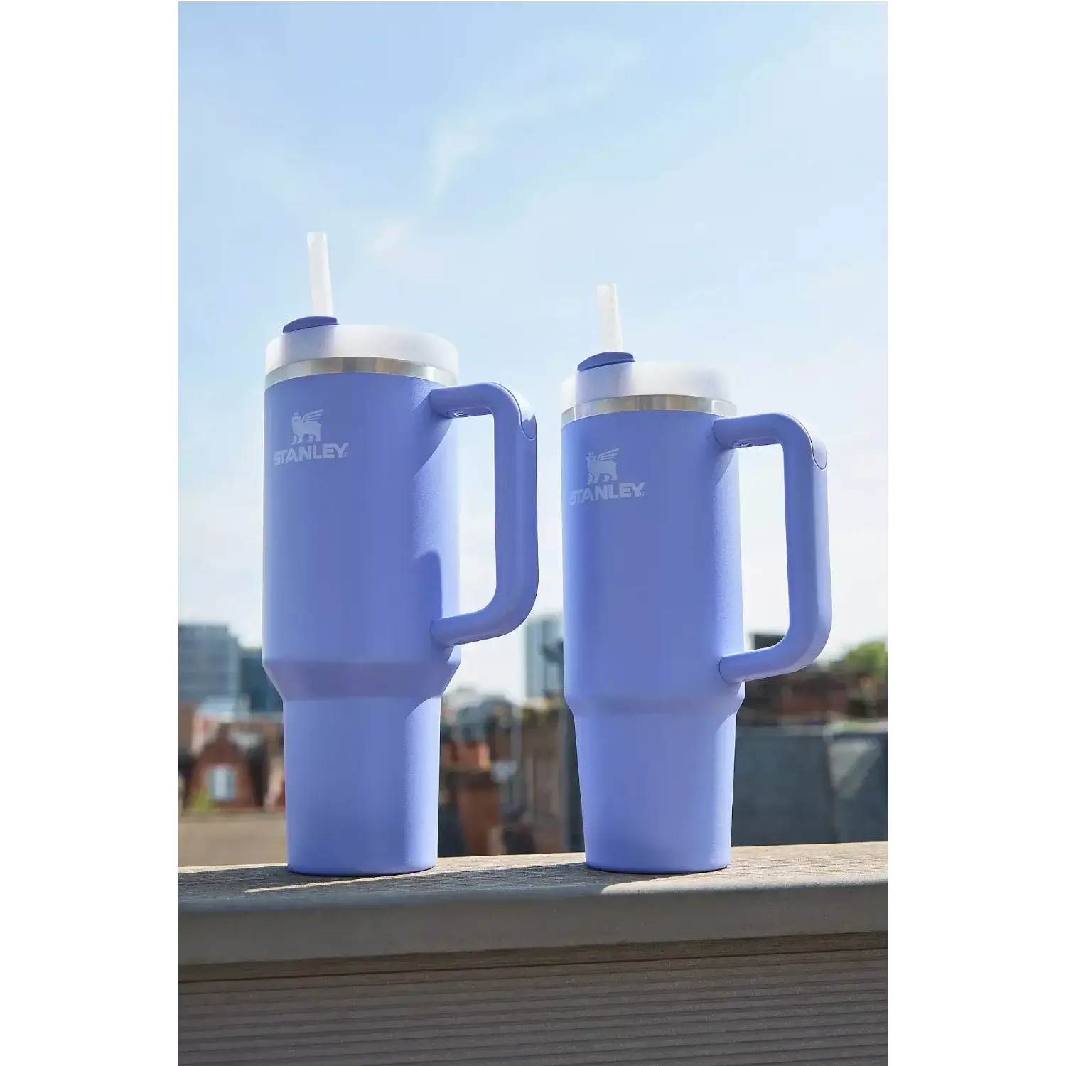 Duas unidades do Copo Quencher Stanley 887ml em um parapeito ao ar livre, destacando o design funcional e icônico.