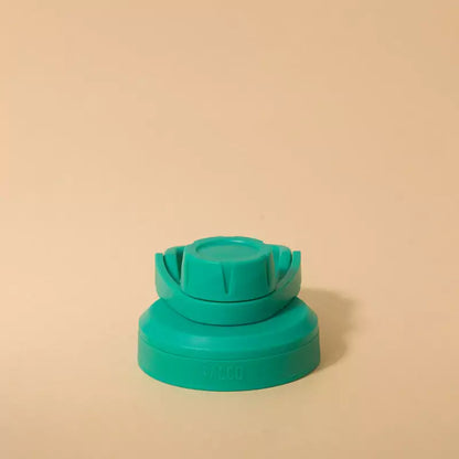 Tampa PACCO Stiff em polipropileno com vedação de silicone para fechamento hermético e seguro, verde, em fundo bege.