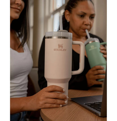 Pessoas usando Copo Quencher Stanley 1,18L na mesa durante o trabalho, destacando design ergonômico e durabilidade.