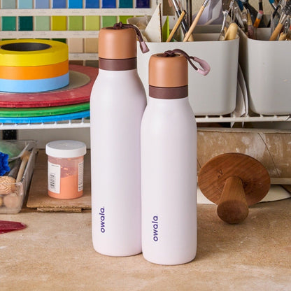 Garrafa Térmica Owala Twist - 532ml | 18oz em uma bancada de trabalho com fundo de materiais de arte.