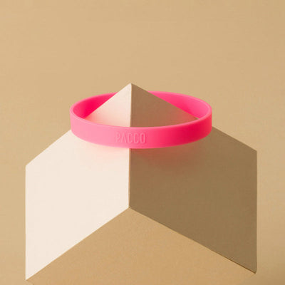 Anel de Silicone PACCO em rosa sobre bloco geométrico, destacando conforto e estilo para garrafas. Ideal para pegada ergonômica.