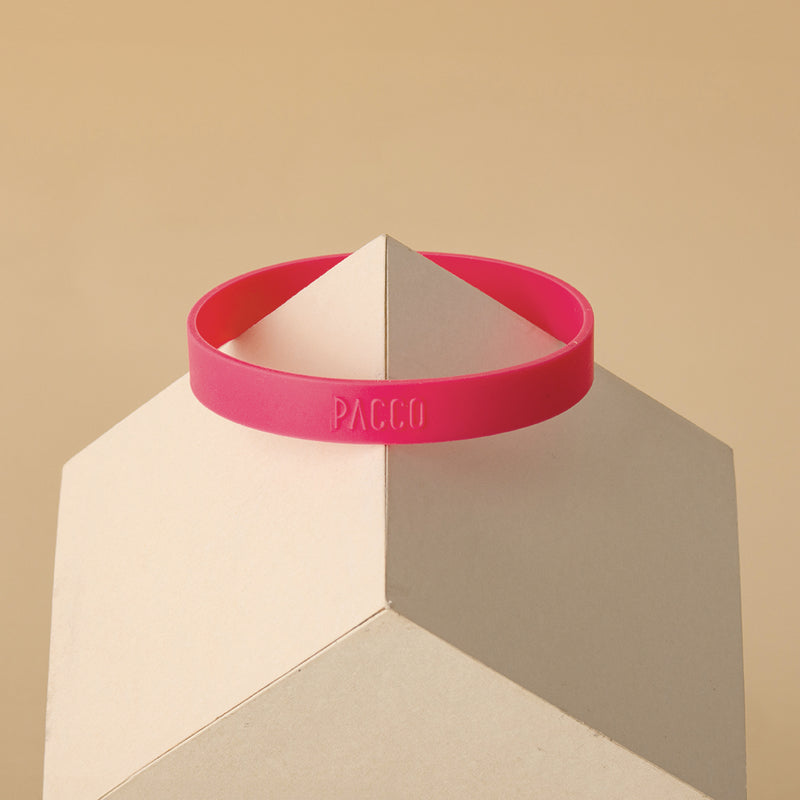 Anel de Silicone PACCO rosa sobre fundo geométrico, destacando ergonomia e estilo.