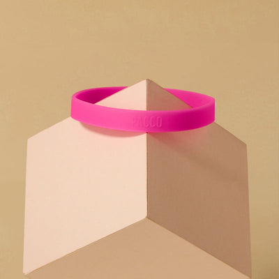 Anel de Silicone PACCO rosa em fundo geométrico, destacando ergonomia e estilo moderno.