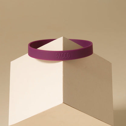 Anel de Silicone PACCO em silicone premium roxo, design ergonômico para conforto e aderência, sobre base geométrica neutra.