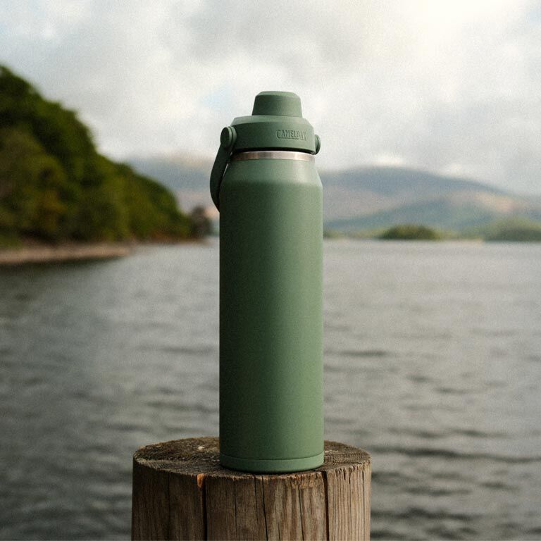 Garrafa Térmica Thrive Camelbak 1,18L em um cenário natural com lago ao fundo.
