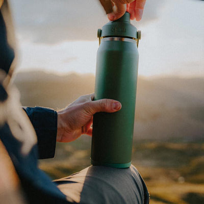 Garrafa Térmica Thrive Camelbak 1,18L sendo segurada por uma pessoa em um cenário ao ar livre.