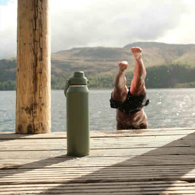 Garrafa Térmica Thrive Camelbak 1,18L em um ambiente natural com pessoa mergulhando ao fundo.