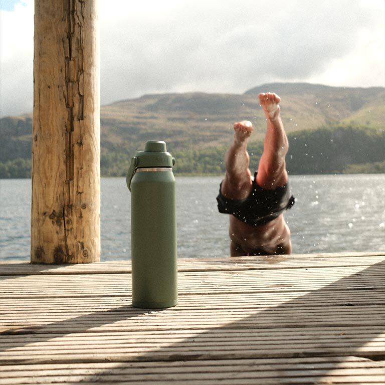 Garrafa Térmica Thrive Camelbak 1,18L em um ambiente natural com pessoa mergulhando ao fundo.