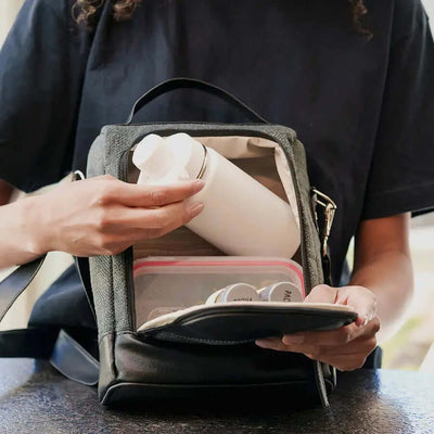 Pessoa colocando uma Garrafa Térmica PACCO Hydrav2 350ml em uma bolsa, destacando portabilidade e design compacto.