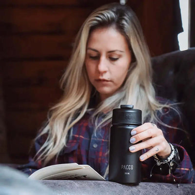 Mulher segurando Garrafa Térmica PACCO Hydrav2 350ml enquanto lê um livro, destacando design elegante e praticidade.