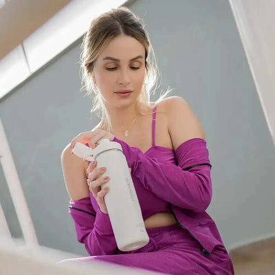 Mulher segurando Garrafa Térmica PACCO Hydrav2 650ml em ambiente interno elegante.