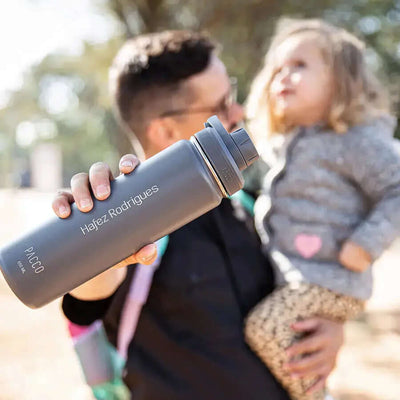 Pessoa segurando Garrafa Térmica PACCO Hydrav2 650ml em um parque, mostrando design ergonômico e estilo sofisticado para uso diário.