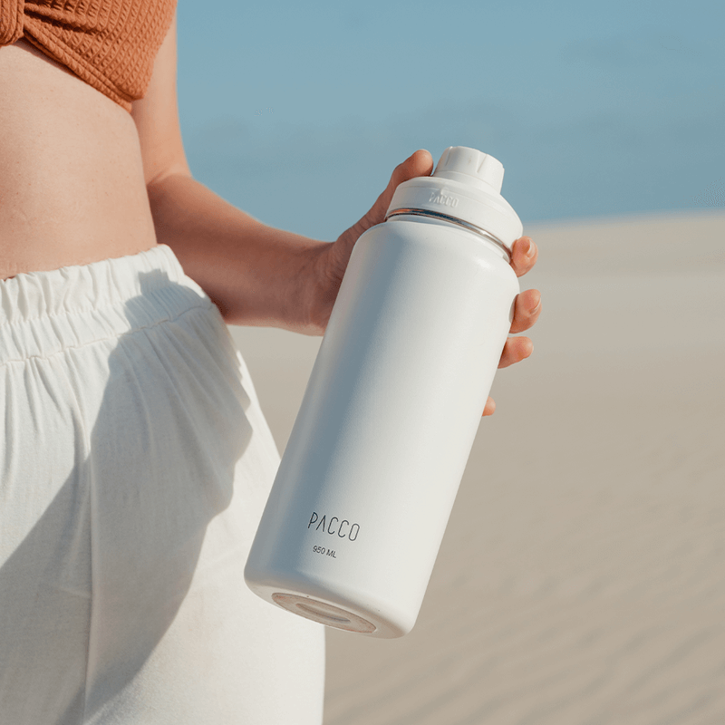 Pessoa segurando Garrafa Térmica PACCO Hydrav2 950ml em um cenário de deserto, destacando design moderno e capacidade térmica.