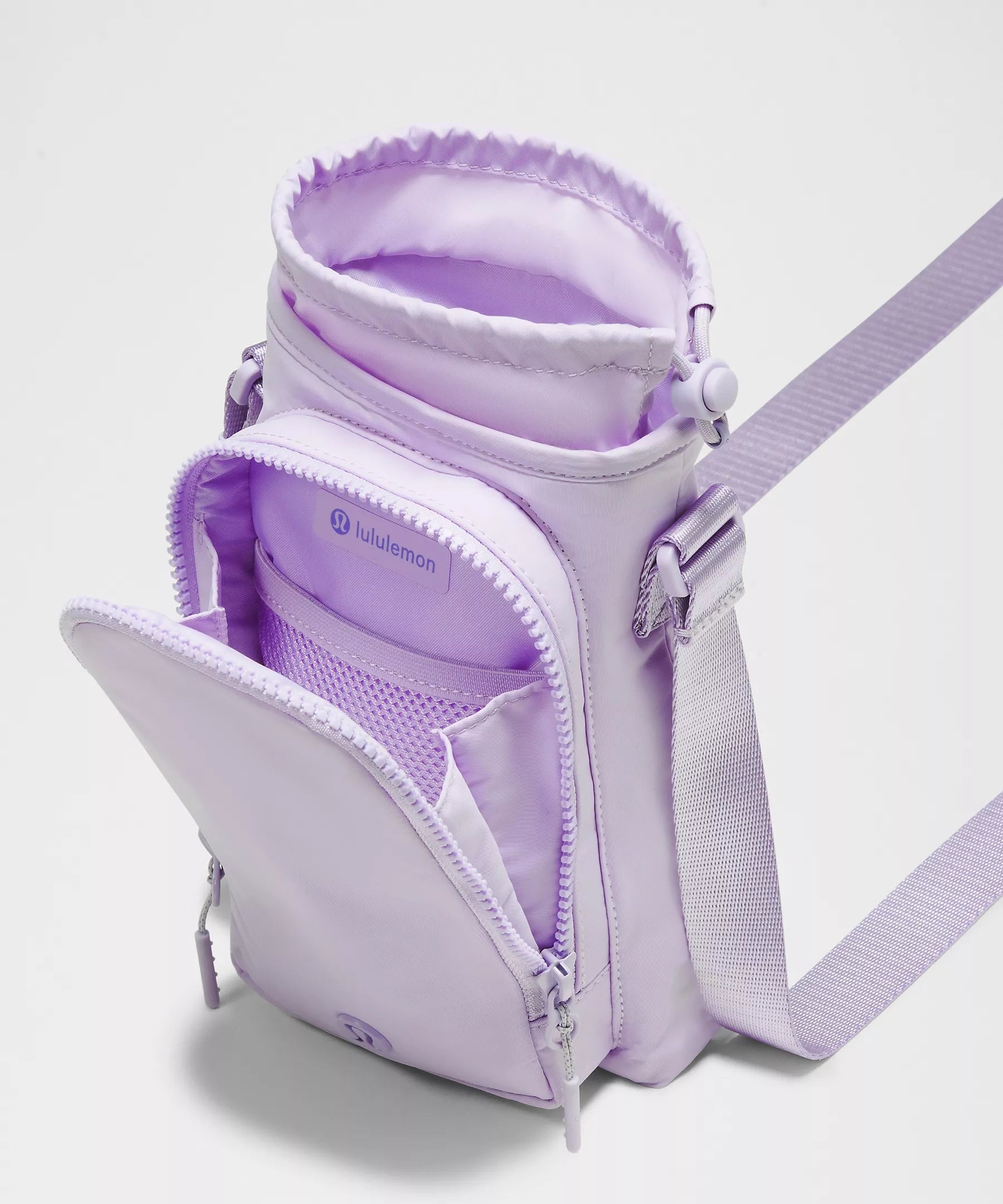 Bolsa para Garrafa Térmica - Cross Bottle Lululemon em lilás, com compartimentos para celular e itens essenciais, ideal para mobilidade.