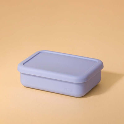 Lunch Box em Silicone - PACCO roxa em fundo bege, ideal para refeições organizadas e portáteis, feita de silicone ecológico, compacta e dobrável.