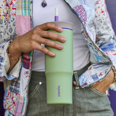 Pessoa segurando Copo Tumbler Térmico Owala - 710ml | 24oz verde, com design moderno e capacidade de manter a temperatura da bebida.