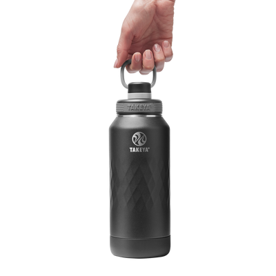 Garrafa Térmica Takeya 950ml Spout Lid Sport sendo levantada por uma mão, ideal para esportes e atividades ao ar livre.