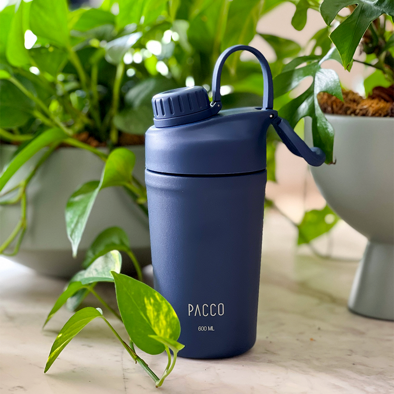Copo Térmico PACCO Shaker 600ml em ambiente natural com plantas ao redor.