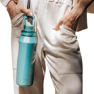 Pessoa segurando Garrafa Térmica Vyta 950ml PACCO | PEDRAS PRECIOSAS em ambiente casual, mostrando design e elegância.