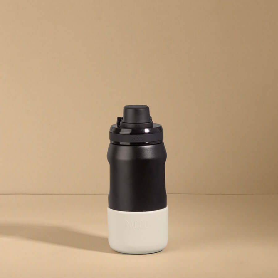 Capa vyta PACCO 350ml preta em silicone sustentável, ideal para proteção e estilo da garrafa, sobre fundo bege.