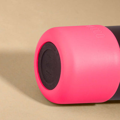 Capa Vyta PACCO 650ml em silicone sustentável, rosa, garantindo proteção e estilo para garrafas, em close lateral com fundo bege.