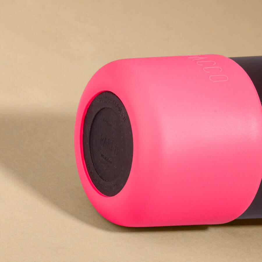 Capa Vyta PACCO 650ml em silicone sustentável, rosa, garantindo proteção e estilo para garrafas, em close lateral com fundo bege.