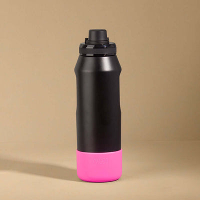 Capa Vyta PACCO 950ml em preto com base rosa vibrante, feita de silicone sustentável, para proteção e design moderno de garrafas.
