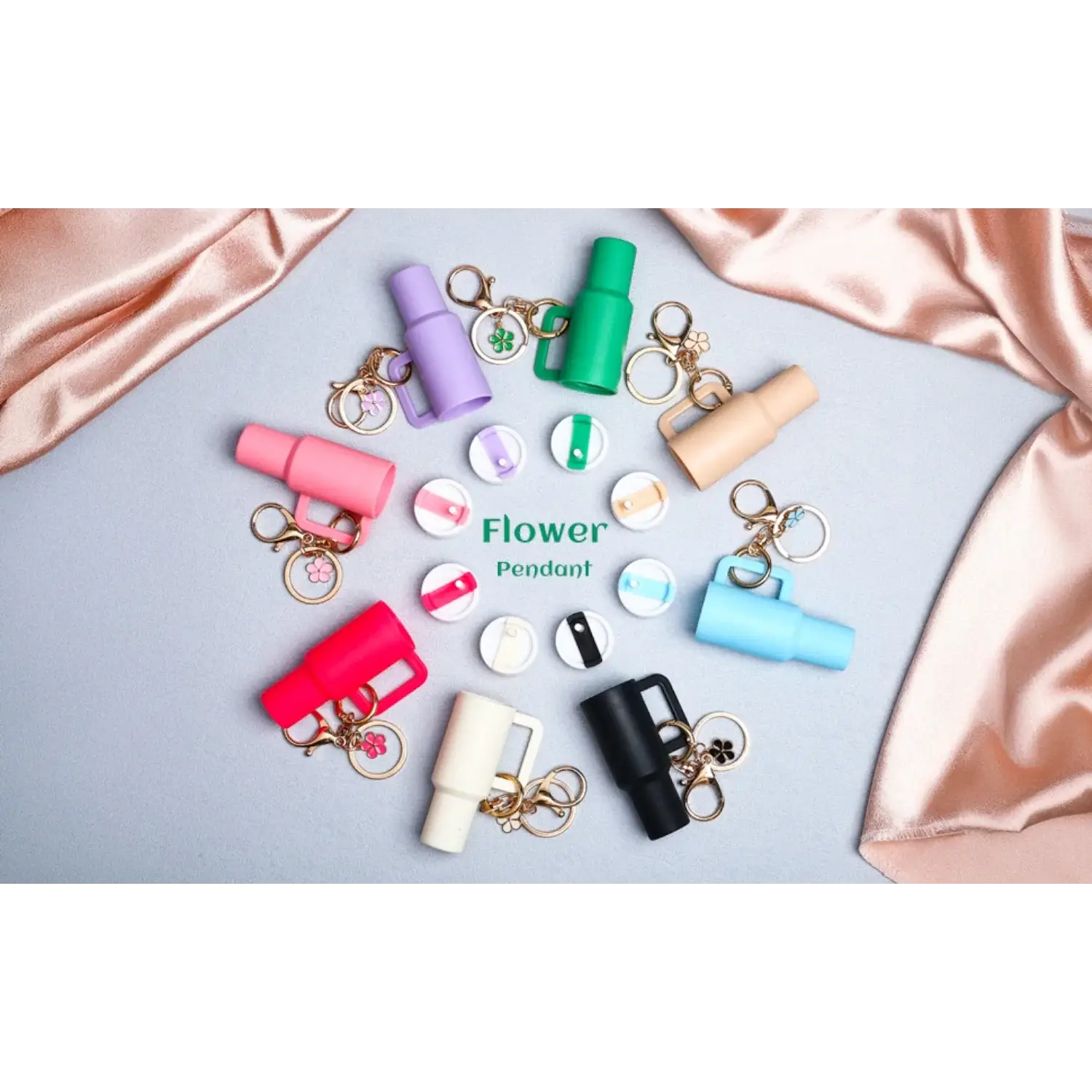 Chaveiro Copo Stanley Quencher em várias cores exibidos sobre tecido, com design miniatura, ideal para colecionadores.