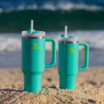 Dois Copos Quencher Stanley 1,18L na praia destacando hidratação com estilo e durabilidade em design icônico e ergonômico.