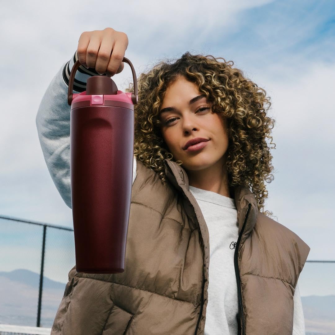 Mulher segurando a Garrafa Térmica Owala FreeSip Sway - 887ml em um ambiente externo, destacando design e praticidade.