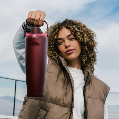 Mulher segurando a Garrafa Térmica Owala FreeSip Sway - 887ml em um ambiente externo, destacando design e praticidade.