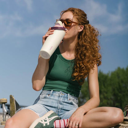 Mulher usando Garrafa Térmica Owala FreeSip Sway - 887ml em um dia ensolarado, destacando estilo e praticidade.