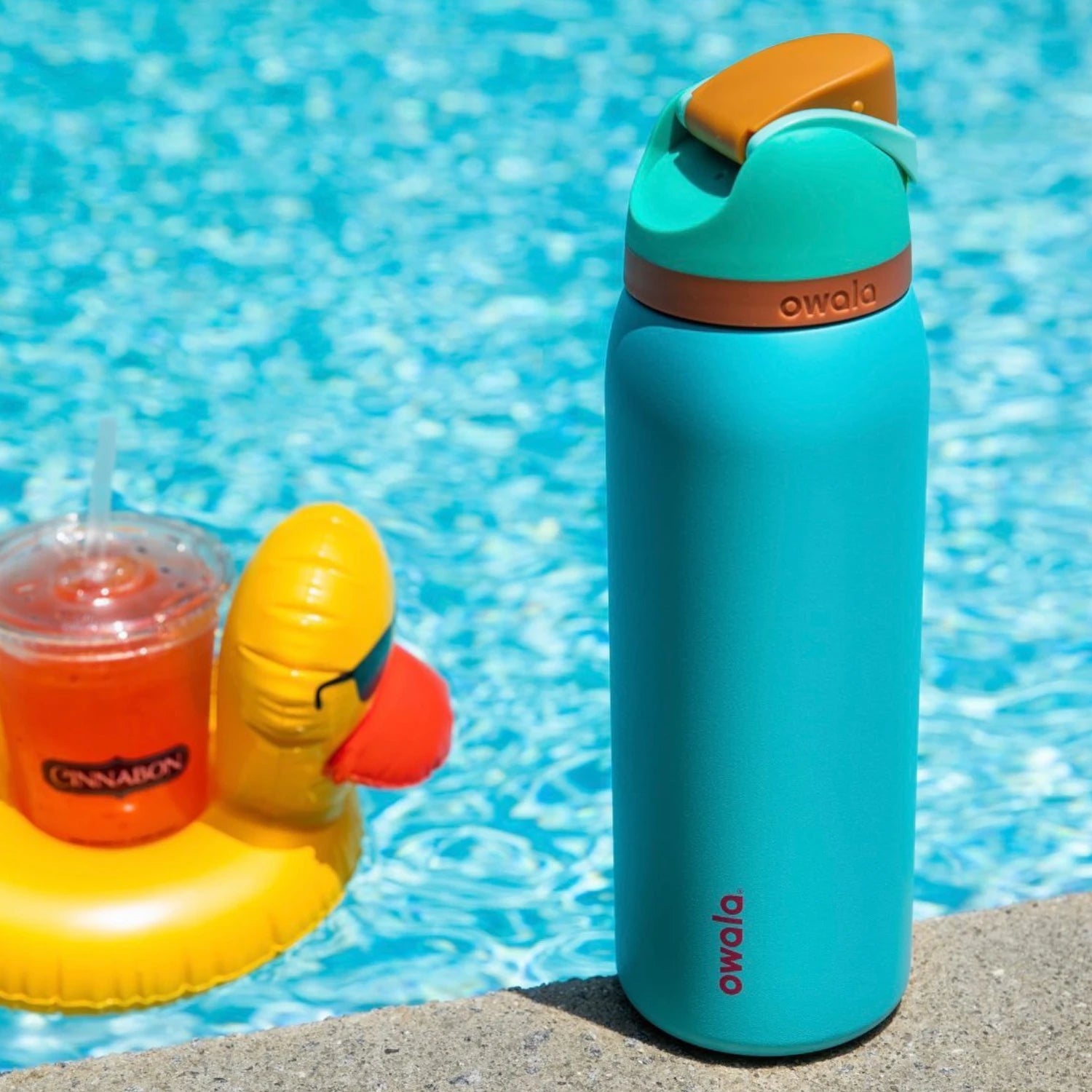 Garrafa Térmica Owala FreeSip - 1180ml | 40oz ao lado de uma piscina, destacando seu design moderno e tampa inovadora.
