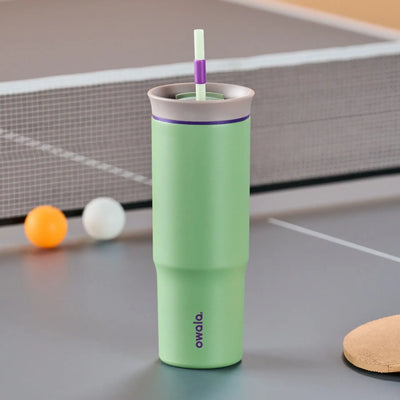 Copo Tumbler Térmico Owala - 710ml | 24oz, com design verde claro, na mesa de pingue-pongue.