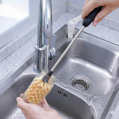 Homem usando o Kit de Escovas para Limpeza de Garrafas, Canudos e Tampas para limpar um frasco sob a torneira.