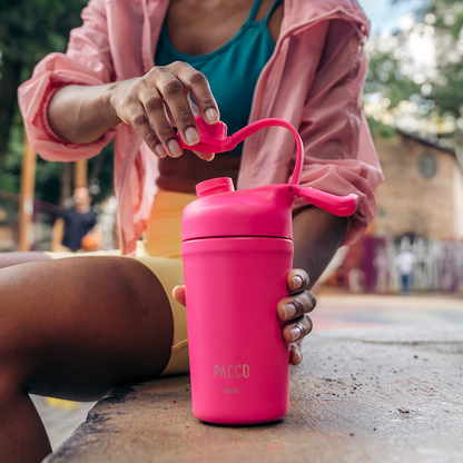 Pessoa segurando Copo Térmico PACCO Shaker 600ml rosa, em ambiente externo, ideal para manter bebidas na temperatura ideal.