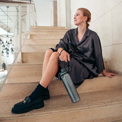 Mulher sentada segurando Garrafa Térmica Vyta 650ml PACCO | PEDRAS PRECIOSAS, design elegante e sustentável.